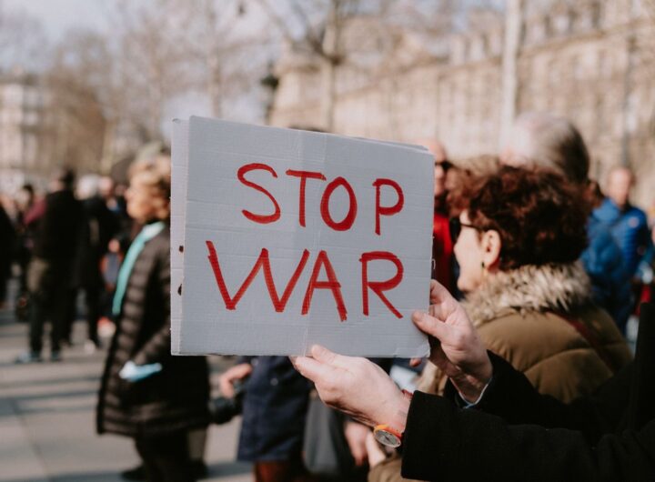 Crowd of people in a peaceful protest holding a 'Stop War' sign outdoors.