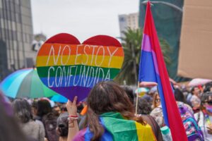 Vibrant LGBT pride gathering in Mexico City featuring rainbow flags and a heart-shaped placard.