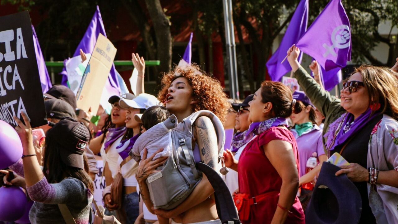 Vibrant street march showcasing unity and feminism under vibrant purple flags.