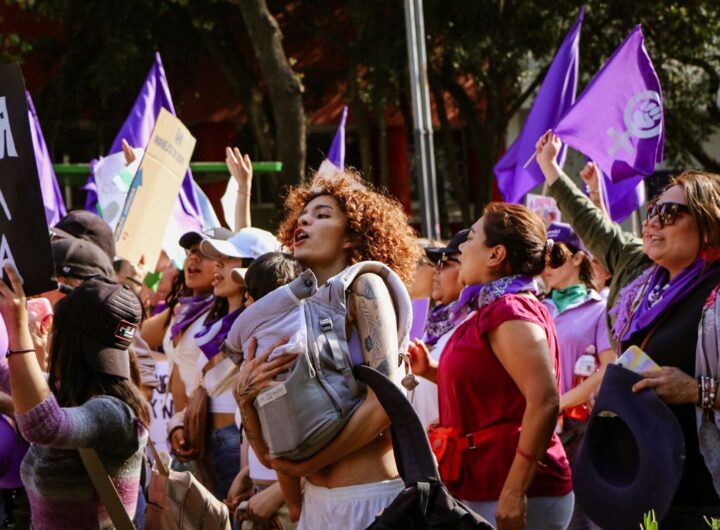 Vibrant street march showcasing unity and feminism under vibrant purple flags.