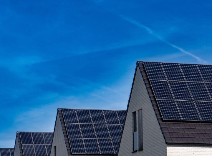 Contemporary homes featuring solar panels under a bright blue sky promoting renewable energy.