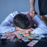 Depressed man surrounded by Argentine pesos represents financial stress and burnout.