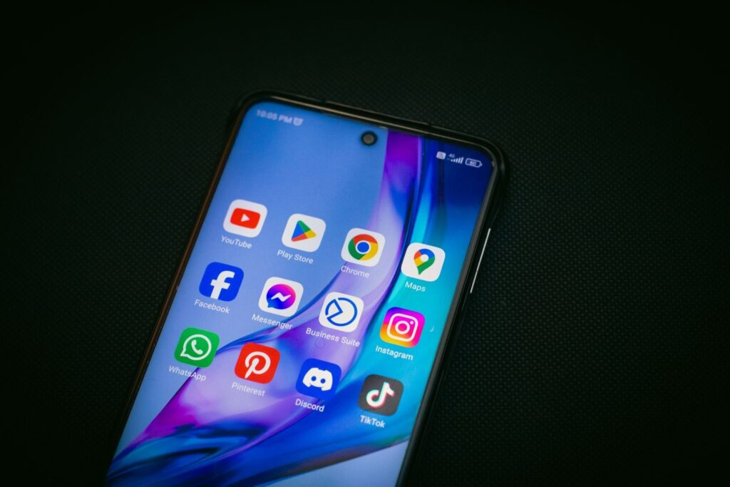 Close-up of a smartphone screen showing popular app icons like YouTube, Maps, and TikTok on a black background.