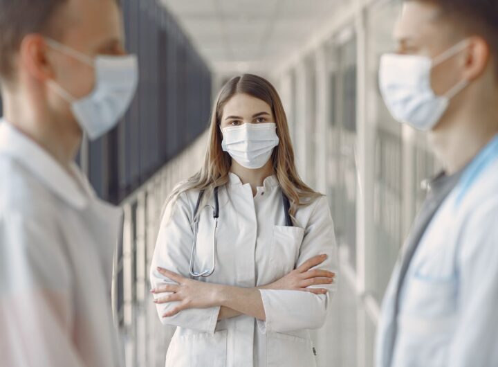 Medical professionals wearing face masks in a hospital hallway.