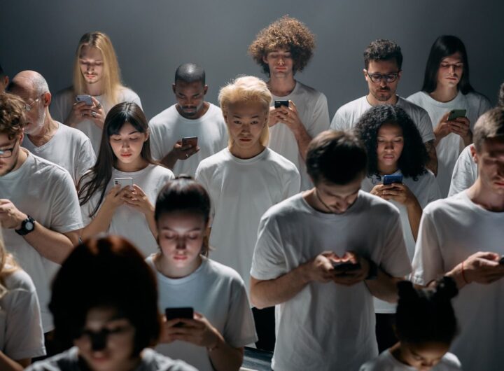 A diverse group of people focused on smartphones indoors, highlighting modern technology's impact.