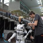 Technician working on humanoid robot at a tech exhibition in Guimaraes, Portugal.