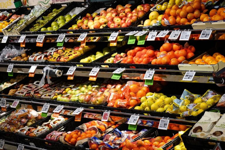 Colorful assortment of fresh fruits neatly arranged on supermarket shelves, ideal for healthy eating themes.