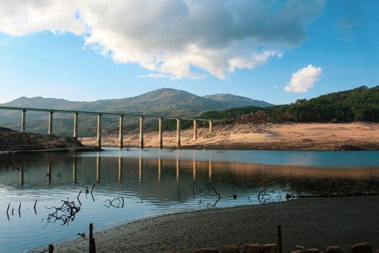 Vivid landscape of Aceredo village with a modern bridge reflecting in the reservoir.